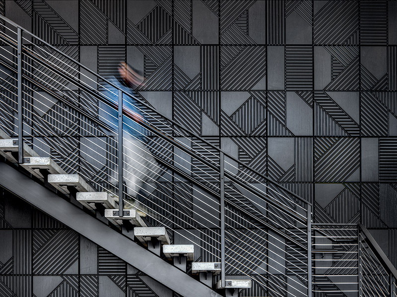 Dark angular geometric wall panels as staircase backdrop