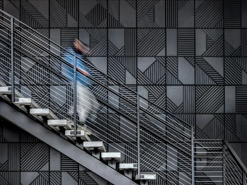 Dark angular geometric wall panels as staircase backdrop