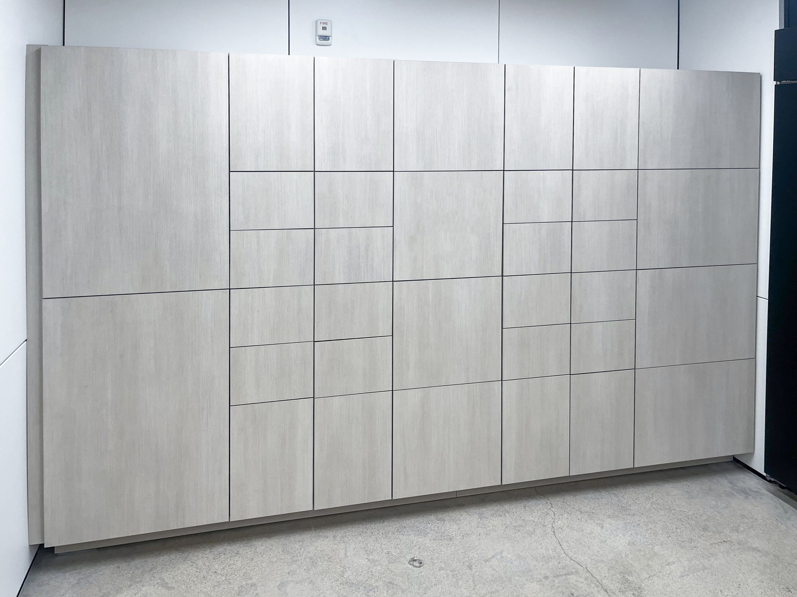 Full wall of pale gray-white lockers in showroom setting