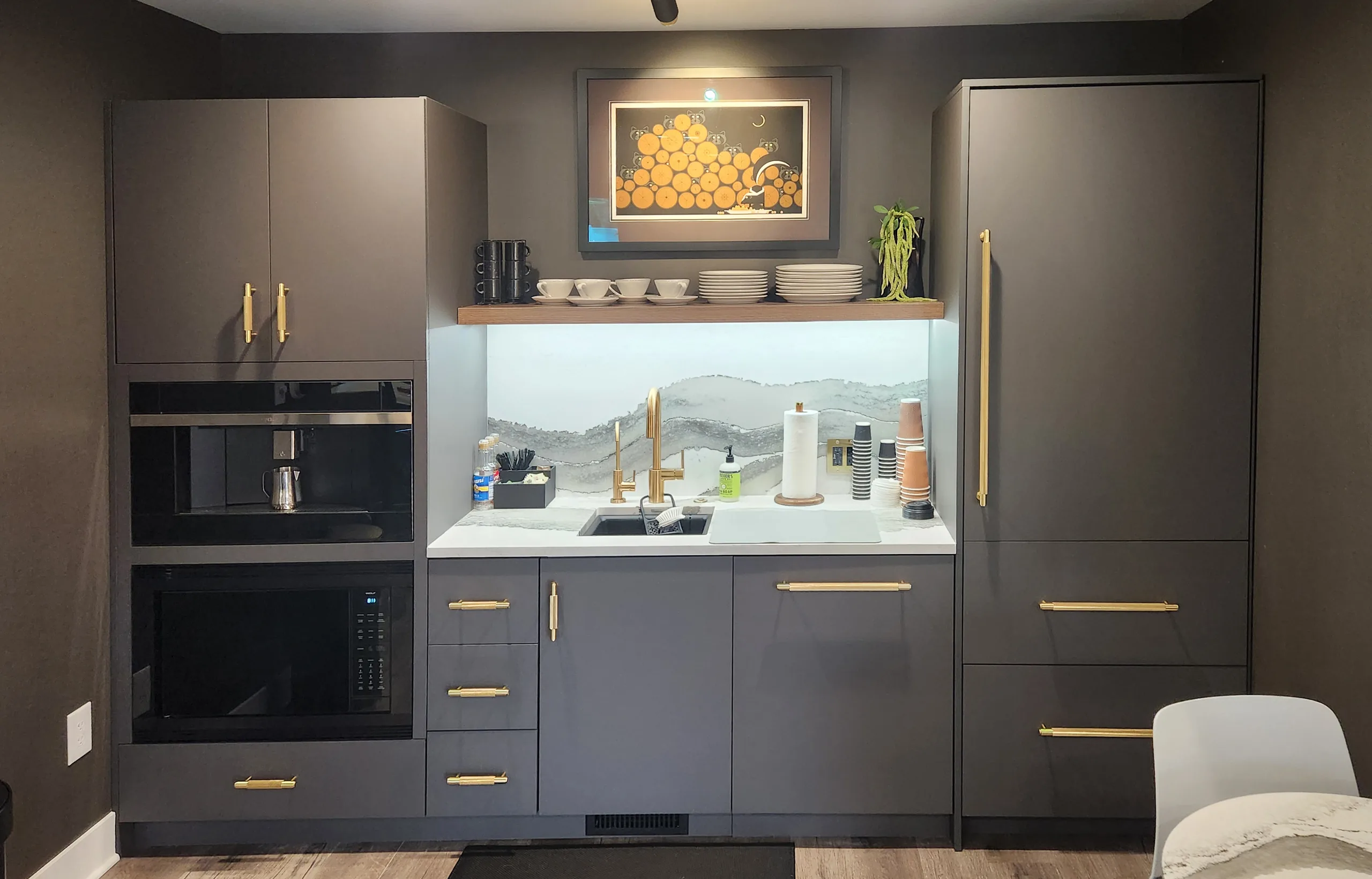 Dark FENIX casework kitchenette with gold hardware, integrated appliances, and marble countertop