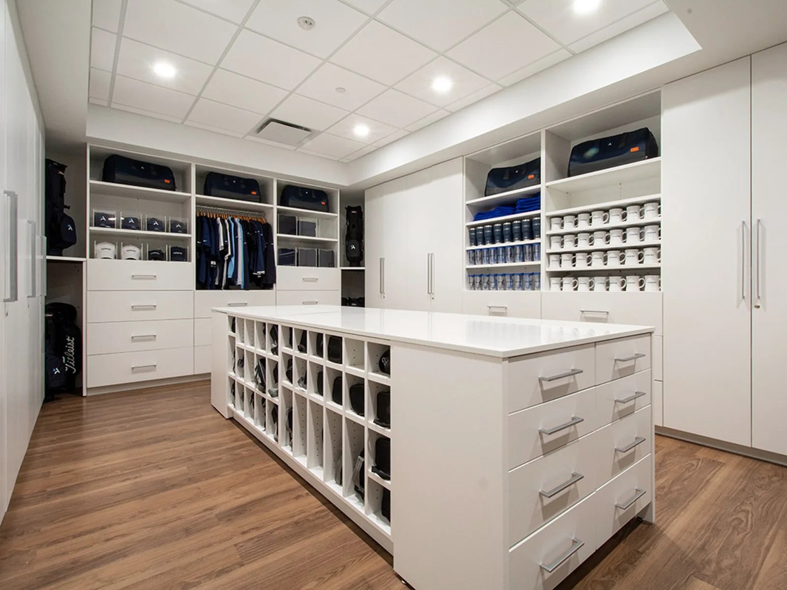 White storage island with open cubbies and drawer banks, casework surround behind