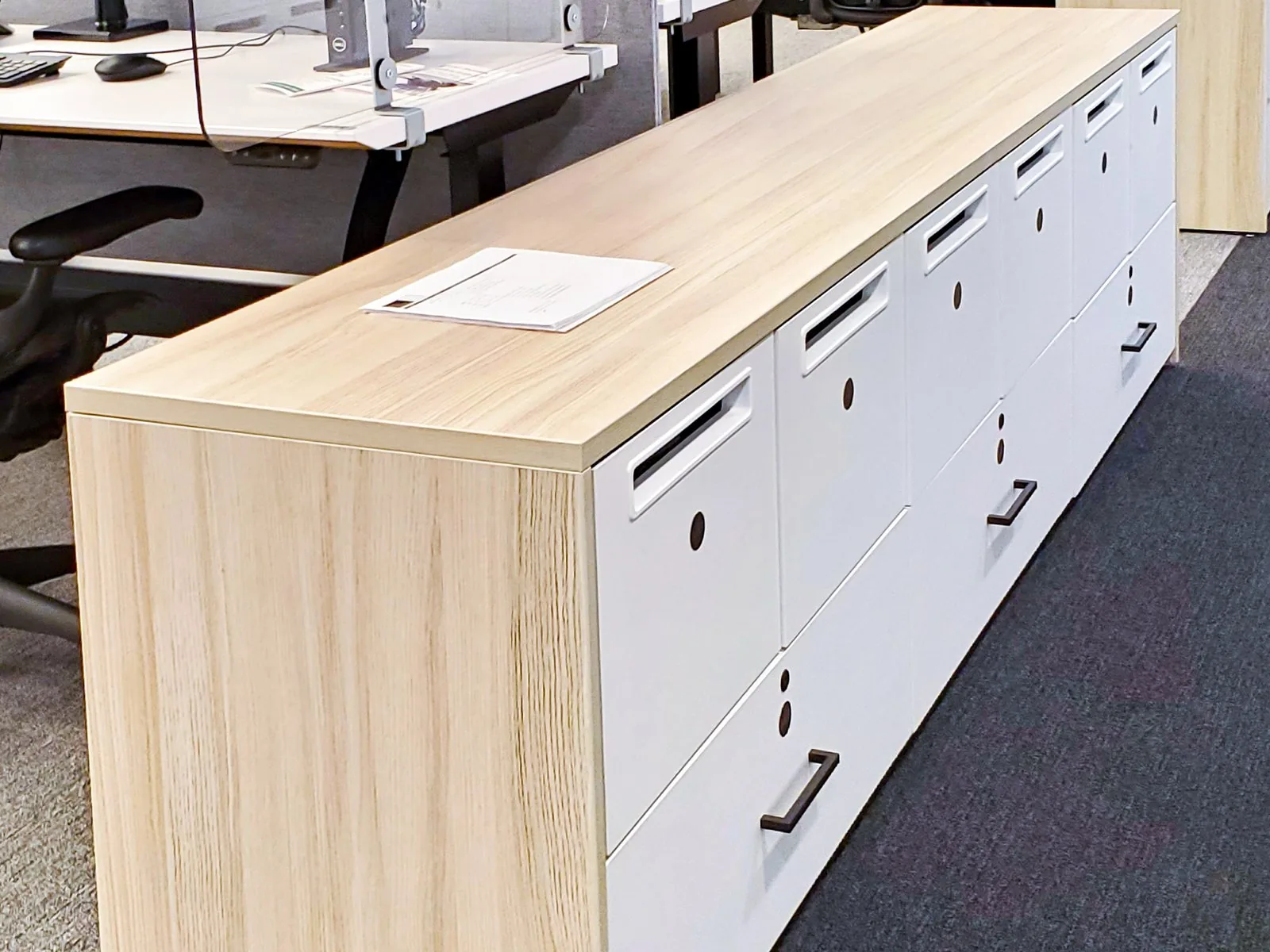 White end-cap lockers with a pale wood top capping a run of workstations