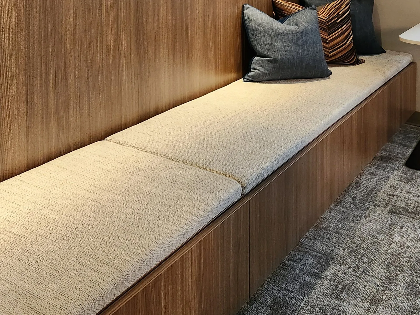 Upholstered bench seat built into a walnut wall with concealed storage below