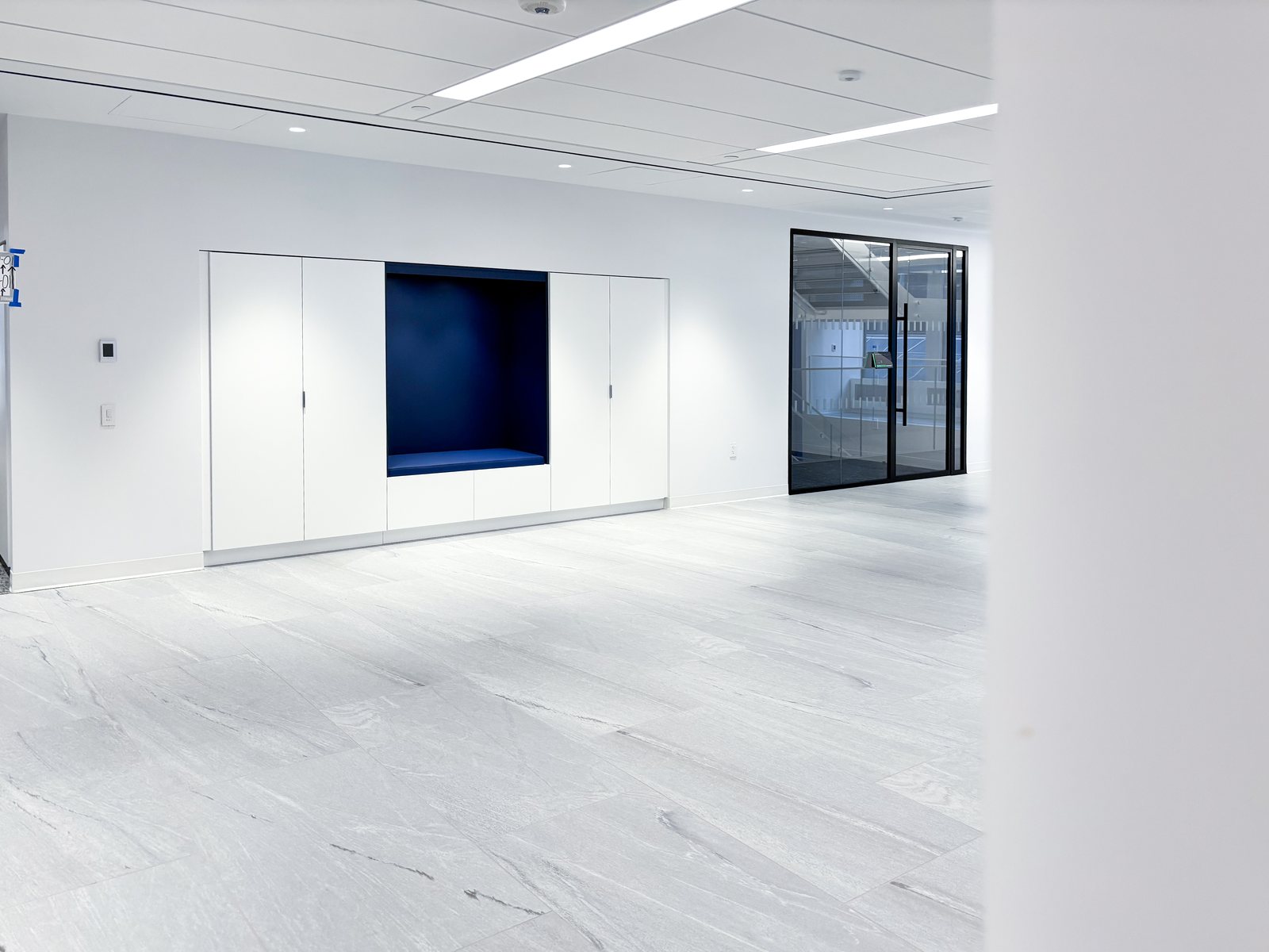Flush white storage wall with a recessed navy niche in a light-filled room
