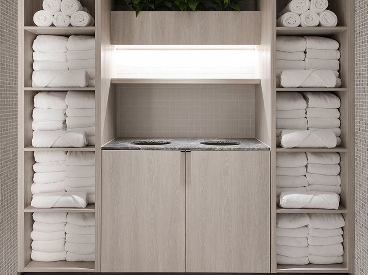 Pale wood towel storage casework with open shelving and a recessed basin counter