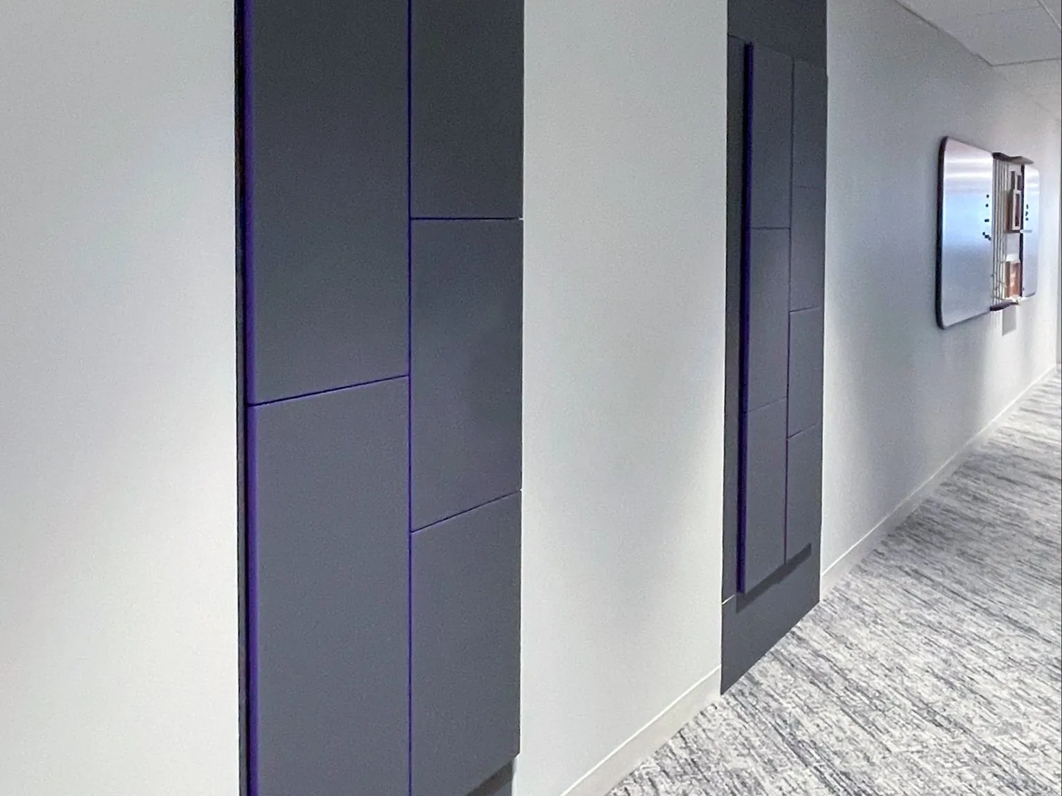 Charcoal locker banks set into a white corridor wall with a fine purple seam detail