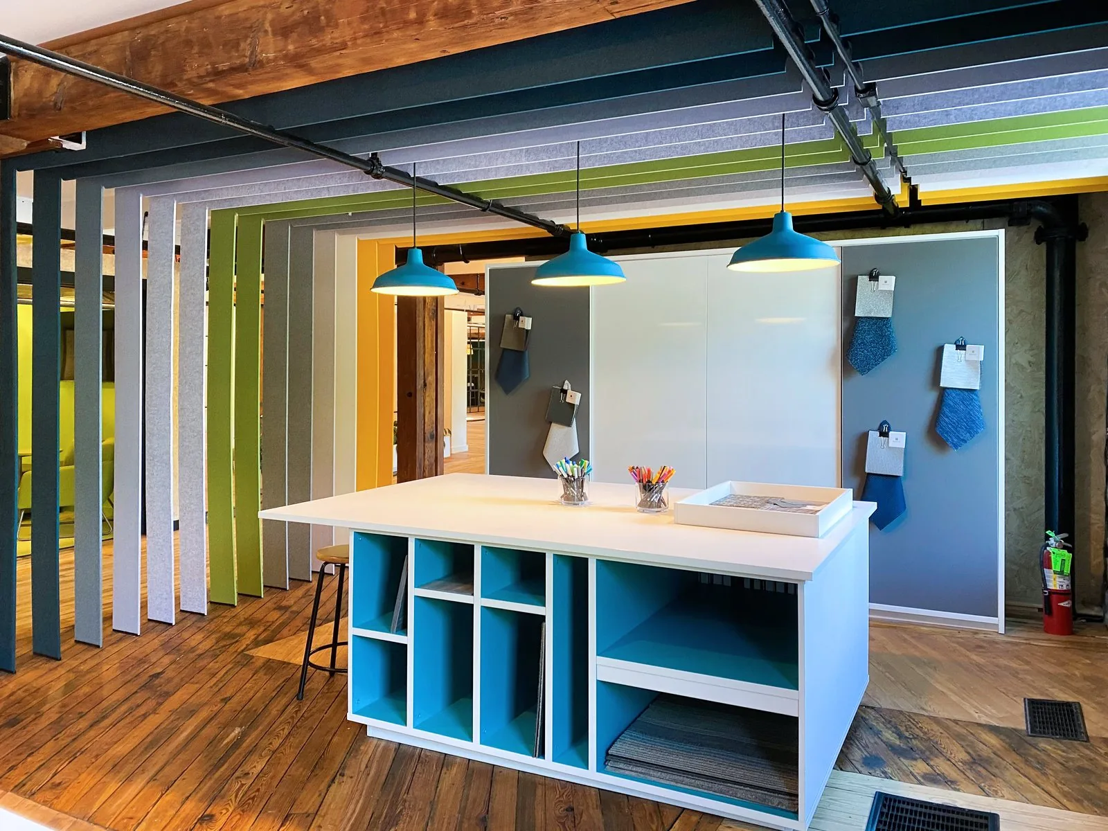 White island with turquoise open cubbies under pendant lighting in a materials showroom