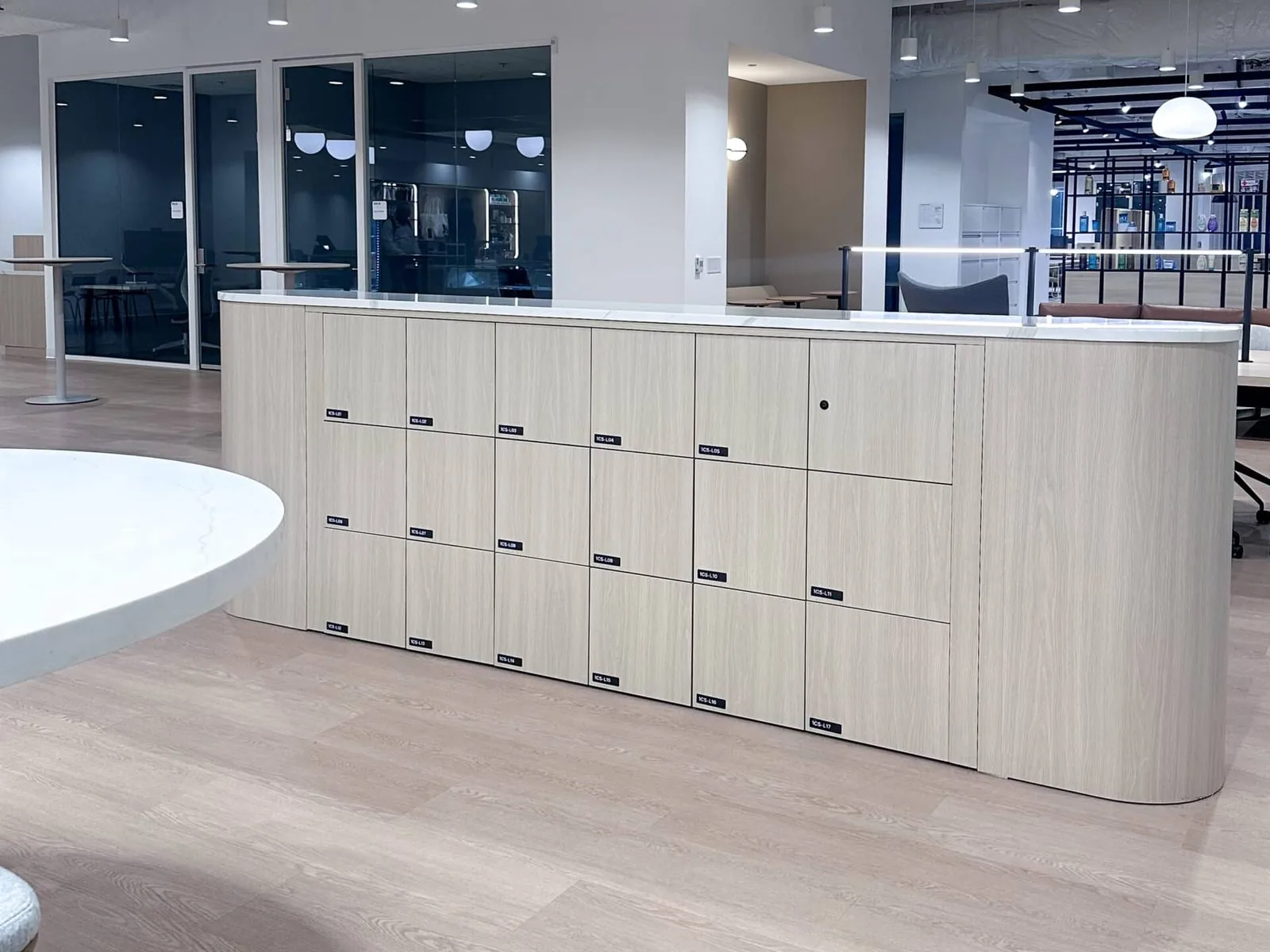 Curved pale wood locker run wrapping the edge of an open-plan floor