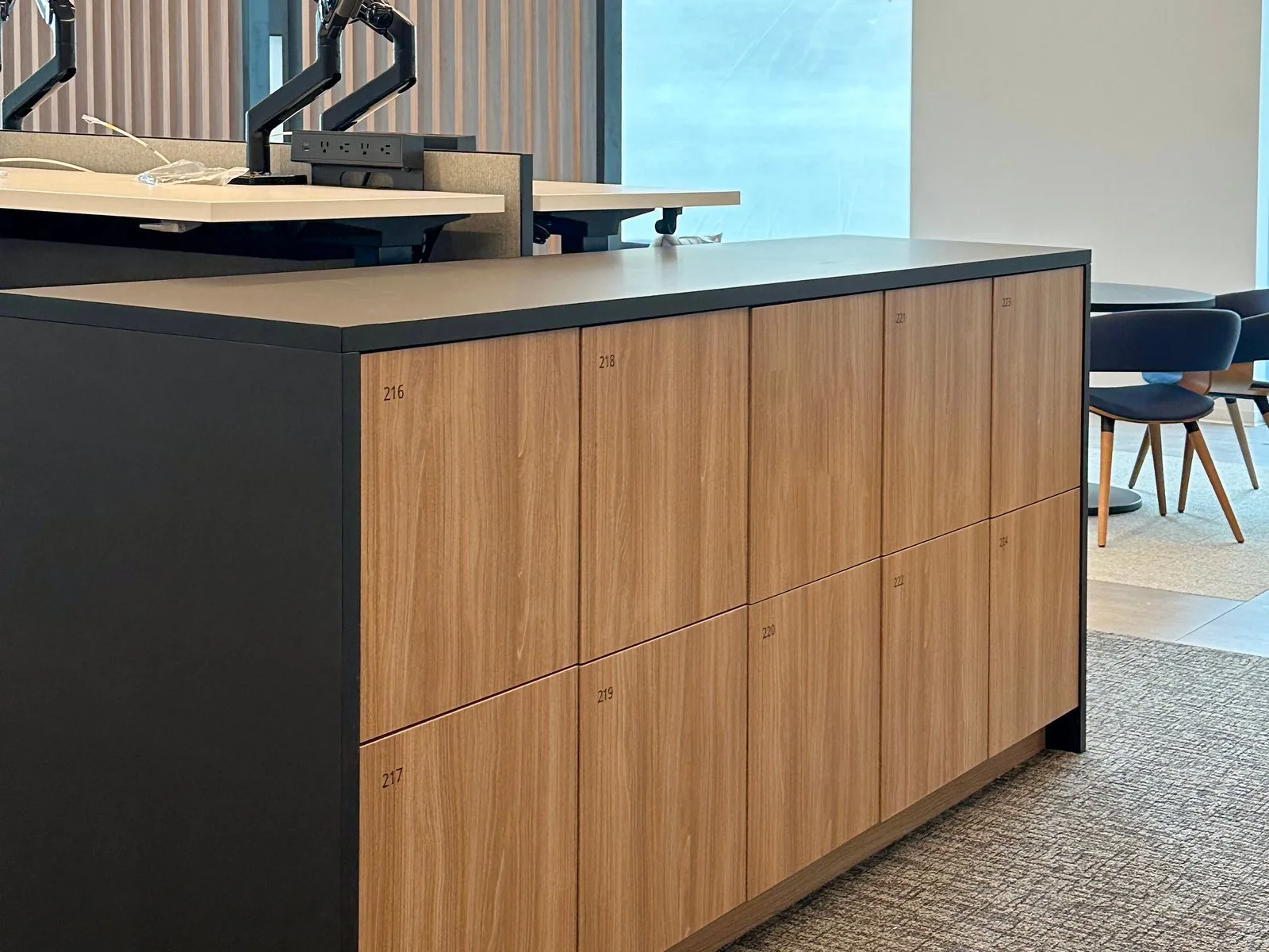 Oak and charcoal end-cap lockers with numbered doors terminating a benching run